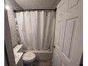 Bathroom with a shower-tub combo with a white curtain, toilet, and white brick-patterned walls at 1903 Rose St., Conway, SC 29527