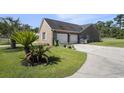 Two car garage next to a yard accented by plants, palms and a grill at 2981 Victor Rd., Longs, SC 29568