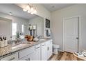 Elegant bathroom featuring double sinks, granite countertops, wood-look flooring, and white cabinetry at 332 Garden Grove St, Conway, SC 29526