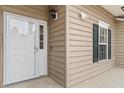 Welcoming entryway featuring a glass panel door, neutral siding, and a classic outdoor light fixture at 411 Mahogany Dr. # 101, Murrells Inlet, SC 29576