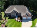 Aerial shot of brick home featuring an attached garage, beautiful landscaping, and lush, mature trees, perfect for serene living at 6572 Wellington Dr., Murrells Inlet, SC 29576