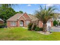 Beautiful brick home showcasing a lush green lawn and landscape, complemented by an inviting outdoor seating area at 702 Compass Pointe Dr, North Myrtle Beach, SC 29582