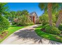 Long driveway leading up to a beautiful brick home surrounded by palm trees and green lawns at 1119 Links Rd., Myrtle Beach, SC 29575