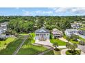 An aerial view showing a charming home nestled in a lush, green environment with ample tree coverage and a nearby waterway at 214 Olde Harbour Ct, Little River, SC 29566