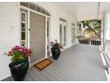 Inviting covered front porch showcases a gray deck, stylish door, and large potted flowers creating a welcoming entrance at 214 Sea Island Dr., Georgetown, SC 29440