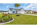 Inviting home with manicured lawn and landscaping featuring a palm tree and colorful flowers at 252 Heath Dr., Longs, SC 29568