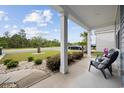 Covered porch with gray chairs, columns, and nicely landscaped front yard with beautiful mature trees at 3573 Bells Lake Circle, Longs, SC 29568