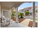 Inviting covered front porch with white rocking chairs and views of the landscaped yard at 4396 Baldwin Ave. # 30, Little River, SC 29566