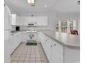 Well-lit kitchen with white cabinets, appliances, and tiled floors, featuring a counter with barstool seating at 4811 Orchid Way # 301, Myrtle Beach, SC 29577