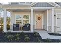 Charming front porch with seating area, landscaped garden, and inviting light pink front door with wreath at 7094 Watercress St, Myrtle Beach, SC 29579