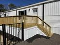 A bright white mobile home with a wooden deck and black iron fence at 2705 Capricorn Dr., Myrtle Beach, SC 29575