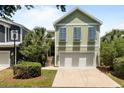 Inviting two-story home with a two-car garage and green exterior, complemented by lush landscaping at 281 Lumbee Circle, Pawleys Island, SC 29585
