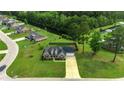 An aerial view showcasing a brick home and its spacious lawn in a tranquil neighborhood with ponds at 301 Farmtrac Dr., Galivants Ferry, SC 29544