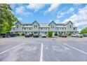 Exterior of a two-story condo complex featuring pale blue siding with an ample parking area and lush green trees behind at 510 Fairwood Lakes Dr. # 923G, Myrtle Beach, SC 29588