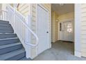 Exterior of a property featuring gray stairs leading to a white door and sidelight, complemented by beige siding at 5822 Longwood Dr. # 104, Murrells Inlet, SC 29576