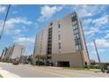 Street view of the condo building with palm trees, a parking garage, and neighboring buildings at 1425 S Ocean Blvd. # 2A, North Myrtle Beach, SC 29582