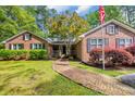 Charming brick home featuring a brick walkway, mature trees, lush landscaping, and a welcoming American flag at 196 John Waites Ct., Georgetown, SC 29440