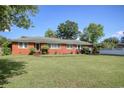 Brick home with a well-maintained lawn, surrounded by mature trees under a clear blue sky at 2004 Seitter St., Georgetown, SC 29440