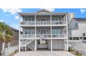 Three-story gray beach house featuring double balconies, white railings, and a charming paver driveway at 204 33Rd Ave. N, North Myrtle Beach, SC 29582