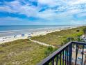 Balcony ocean view overlooking sandy beach with sunbathers under a partly cloudy sky at 2101 S Ocean Blvd. # A-4, North Myrtle Beach, SC 29582