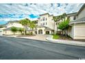 Inviting building entrance features manicured landscaping, sidewalks, and palm trees against a cloudy sky at 2180 Waterview Dr. # 635, North Myrtle Beach, SC 29582