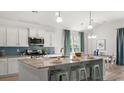 Bright kitchen features granite counters, blue backsplash, island with barstool seating, and stainless appliances at 704 Rupert Dr, Conway, SC 29526