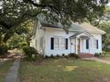 Beautiful white home with classic blue shutters and brick accents, nestled among lush trees at 1403 9Th Ave., Conway, SC 29526