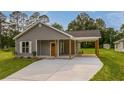 Well-maintained single-story house featuring gray siding, covered parking, and a spacious driveway at 306 S Magnolia Ave., Andrews, SC 29510