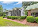 A charming white house featuring a screened-in porch and a brick carport, surrounded by neatly trimmed hedges at 3231 Center Rd., Georgetown, SC 29440