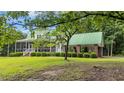 Exterior view of a home with a screened-in porch, a covered parking area, and lush landscaping at 3231 Center Rd., Georgetown, SC 29440