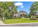 Charming brick home with mature trees, lush landscaping, and well-manicured lawn for serene outdoor living at 383 Oatland Lake Rd., Pawleys Island, SC 29585