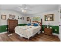 Sunlit bedroom with wooden floors, ceiling fan and a large bed with decorative pillows, offering a cozy retreat at 3839 Woodridge Circle, Little River, SC 29566