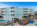 Light blue condo building next to a wooden walkway leading to the beach and outdoor community pool at 824 N Waccamaw Dr. # 203, Murrells Inlet, SC 29576