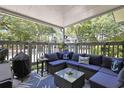 Relaxing covered patio with comfortable wicker seating, anchor themed pillows, a glass top table, and a grill at 88 Salt Marsh Circle # 22F, Pawleys Island, SC 29585