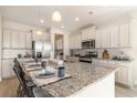 Bright kitchen features white cabinetry, stainless steel appliances, and a granite island with seating at 898 Ireland Dr., Longs, SC 29568