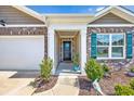 Inviting covered front porch with brick accents, landscaping and a decorative wreath on the front door at 142 Pine Forest Dr., Conway, SC 29526