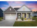 Charming single-story home featuring a manicured lawn, covered porch, and a two-car garage at dusk at 314 Bumble Circle, Murrells Inlet, SC 29576