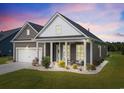 Attractive single-story house with well-kept lawn, front porch seating, and attached two-car garage at dusk at 314 Bumble Circle, Murrells Inlet, SC 29576