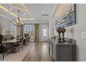 Elegant dining area with chandelier lighting, wood floors, and a large window with decorative curtains at 397 St. Julian Ln., Myrtle Beach, SC 29579