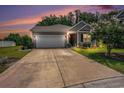 Charming single-story home with a well-manicured lawn, spacious driveway, and attached two-car garage at dusk at 409 Spring View Ct., Little River, SC 29566
