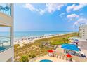 High angle view of a crowded beach and the ocean from a balcony overlooking a pool at 4525 S Ocean Blvd. # 406, North Myrtle Beach, SC 29582
