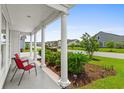 Inviting front porch with classic white columns, a seating area, and manicured landscaping at 4555 Weekly Dr, Myrtle Beach, SC 29579