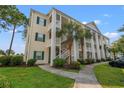 Angle view of the three-story condo building with white columns and balconies, surrounded by trees and grass at 6000 Windsor Green Way # 104, Myrtle Beach, SC 29579