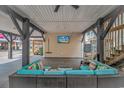 Comfortable outdoor seating area under the stilted home, featuring a cozy sectional and mounted television for entertainment at 6001- 8005 S Kings Hwy., Myrtle Beach, SC 29575
