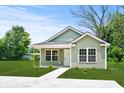 Inviting one-story house with light green siding, a dark roof, a manicured lawn, and a concrete path at 608 Miles Ct, Marion, SC 29571