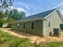 Side view of a light green home with black roof and an AC unit at 608 Miles Ct, Marion, SC 29571