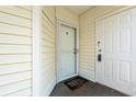 Entrance to unit features a storm door, cream siding, and 'Yay, you're here!' doormat at 1208 River Oaks Dr. # 24-B, Myrtle Beach, SC 29579