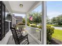Inviting front porch featuring rocking chairs, white railings, and a view of the serene neighborhood street at 136 Southbury Dr., Myrtle Beach, SC 29588