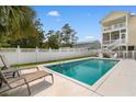 Sparkling private pool with lounge chairs, surrounded by a white fence and lush greenery, creating a backyard oasis at 213 South Myrtle Dr., Surfside Beach, SC 29575