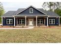 Beautiful blue home featuring dark shutters, a brick base, manicured lawn, and a lovely front porch at 3200 Fowler School Rd., Loris, SC 29569